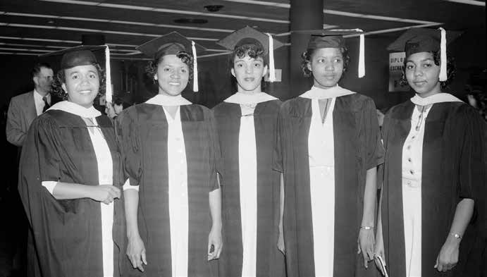 five recent graduates with cap and gowns